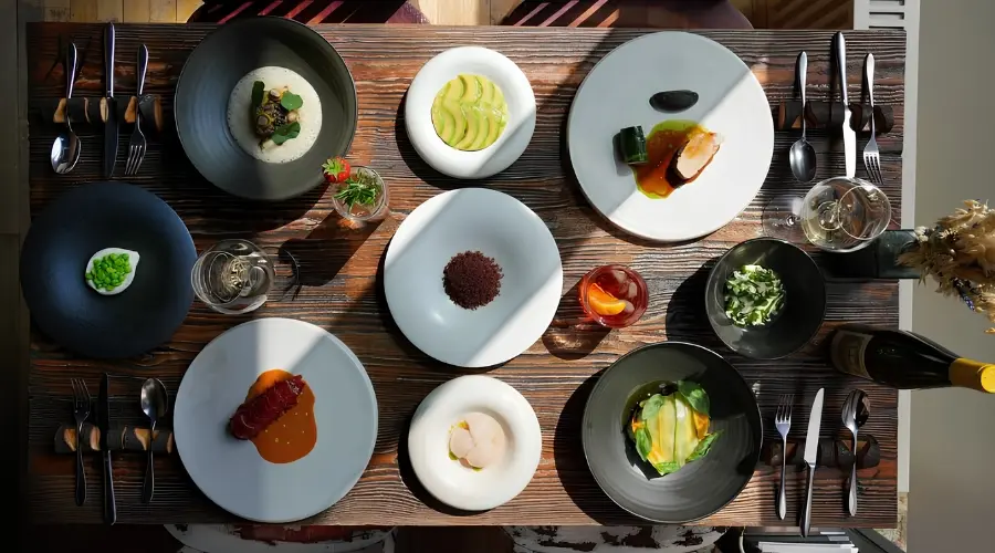 Overhead view of a restaurant table set with multiple plated dishes, drinks and tableware.