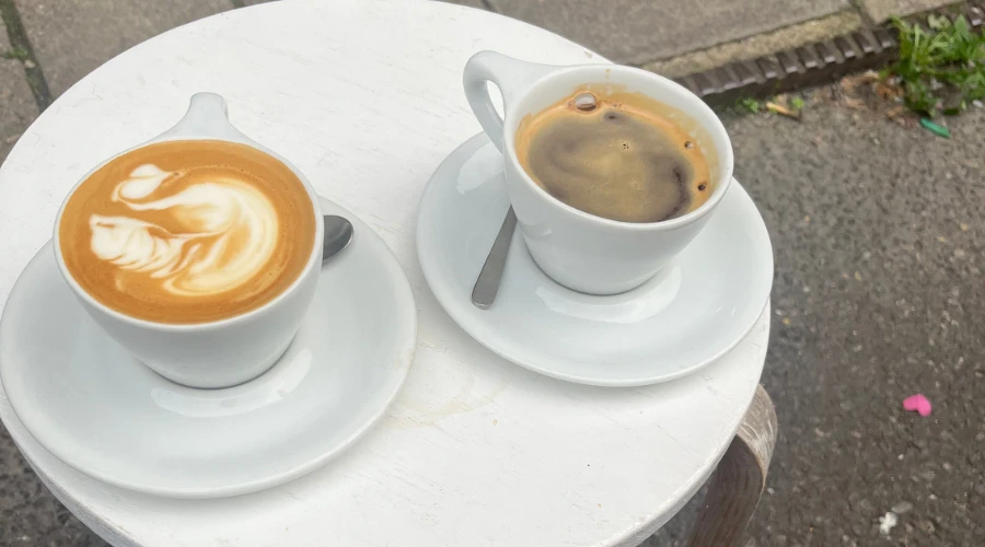 Coffee with latte art swan and black coffee on a table outside