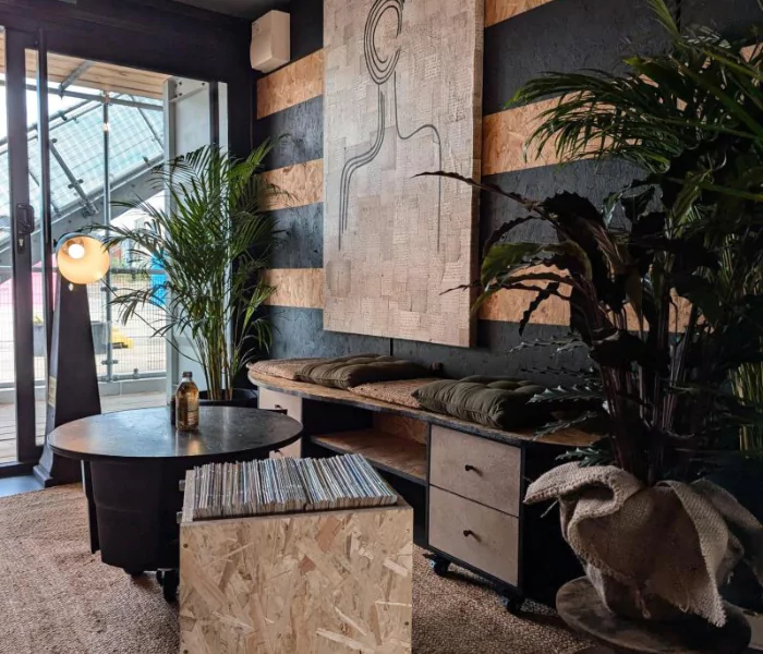 The rustic interior of a small office space at Boxworks Brabazon with natural and black accents and lush green plants.