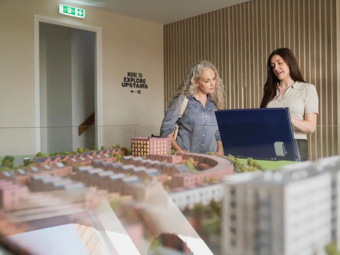 Two people examine a detailed architectural model with buildings of Brabazon.