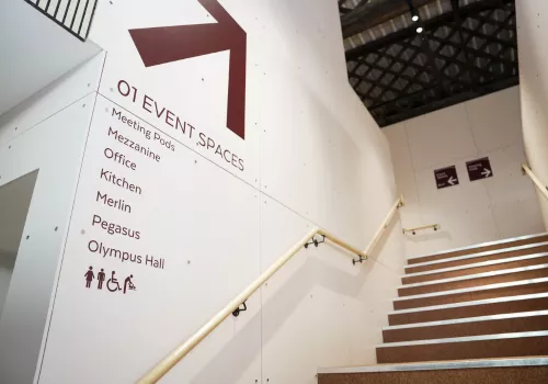 Staircase of the newly renovated Spitfire Hangar with sign pointing to meeting rooms and event spaces.