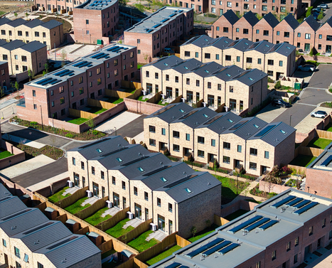 Drone shot of new brick homes with green gardens lining the streets at Brabazon on a sunny day.