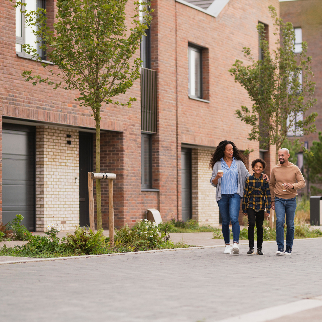 Young family walking smiling and laughing as they walk down a landscaped street at Brabazon.
