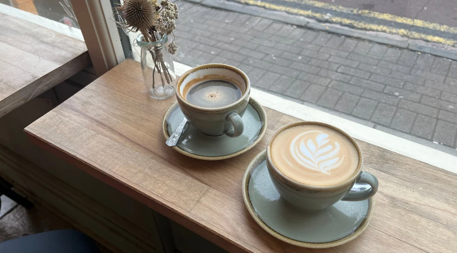 Black coffee and coffee with latte art on window table with street outside