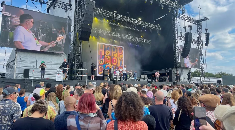 Crowd watching a live band perform on a large outdoor stage at FORWARDS Festival under partly cloudy skies.