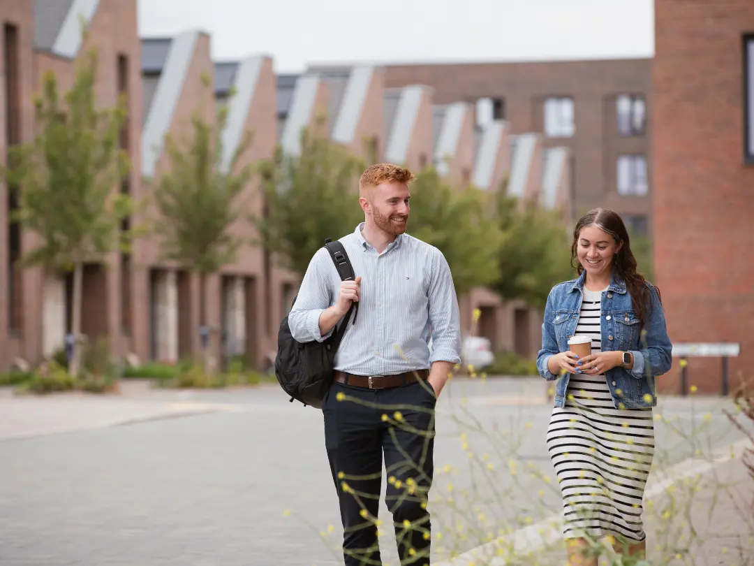 A man and woman walk and chat on a paved path in Brabazon, smiling. 