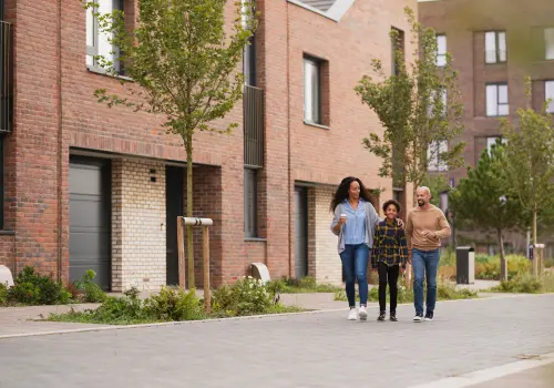Young family walking smiling and laughing as they walk down a landscaped street at Brabazon.