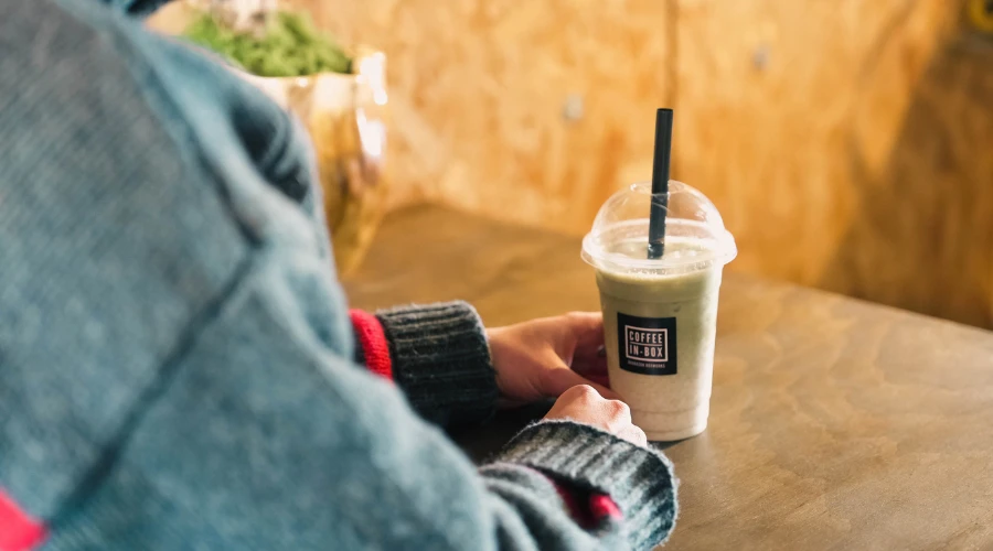 Person holding with a drink in a plastic cup with a straw