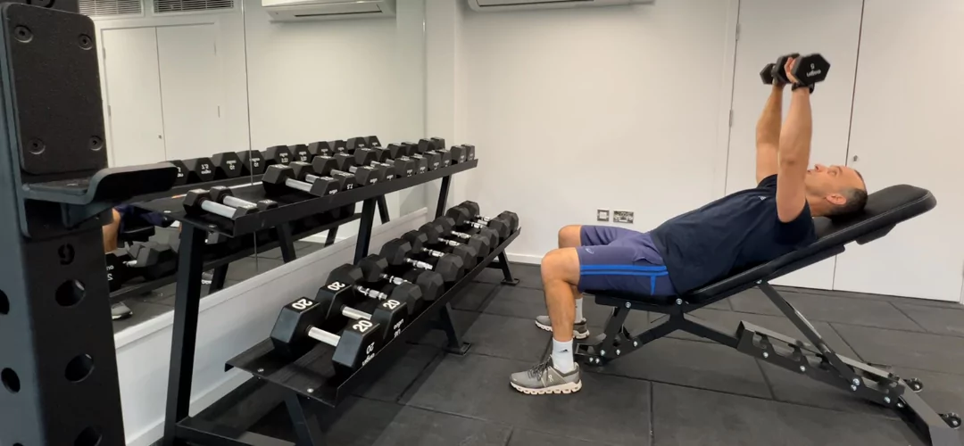 Man preparing for a dumb bell bench press in the residents gym at The Dials. 