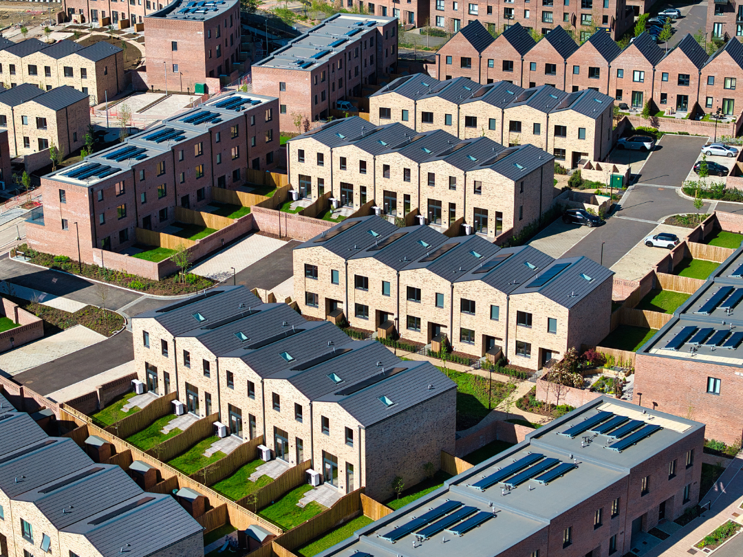 Drone shot of new brick homes with green gardens lining the streets at Brabazon on a sunny day.