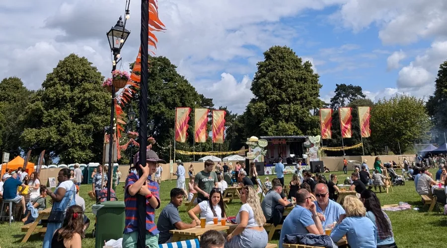 Festival attendees of Feast On relax on the grass, engaging in conversation and enjoying the lively atmosphere of the event.